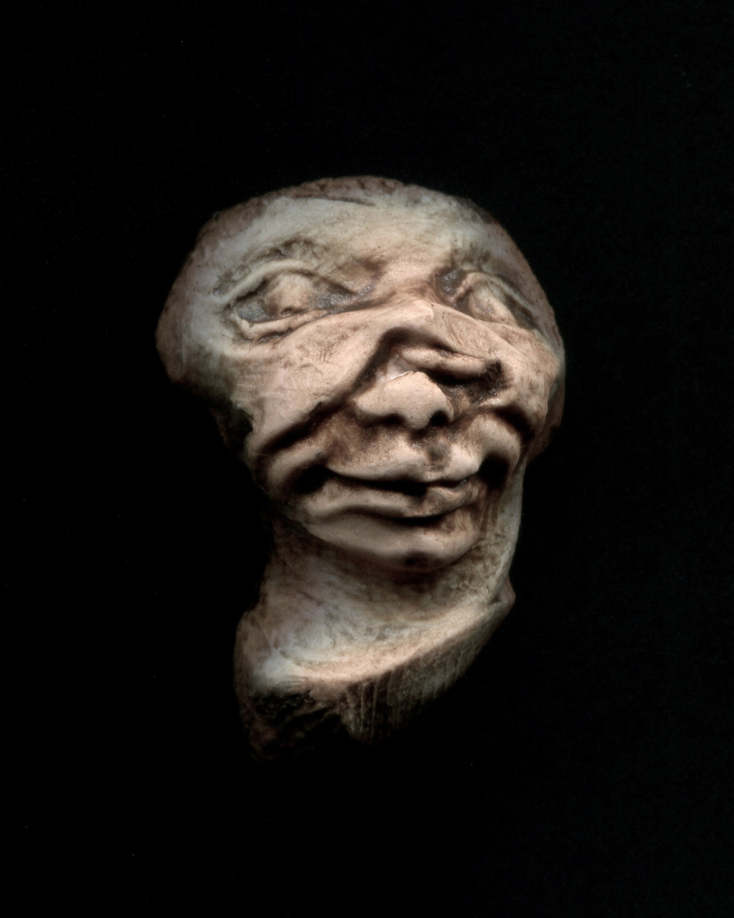 a carved statue of a creepy face on a black background