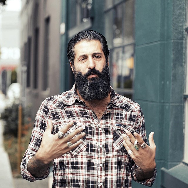 a man with a beard standing next to a tall building