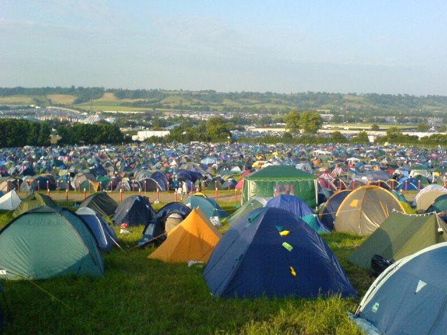 a large lot full of tents and people on the grass