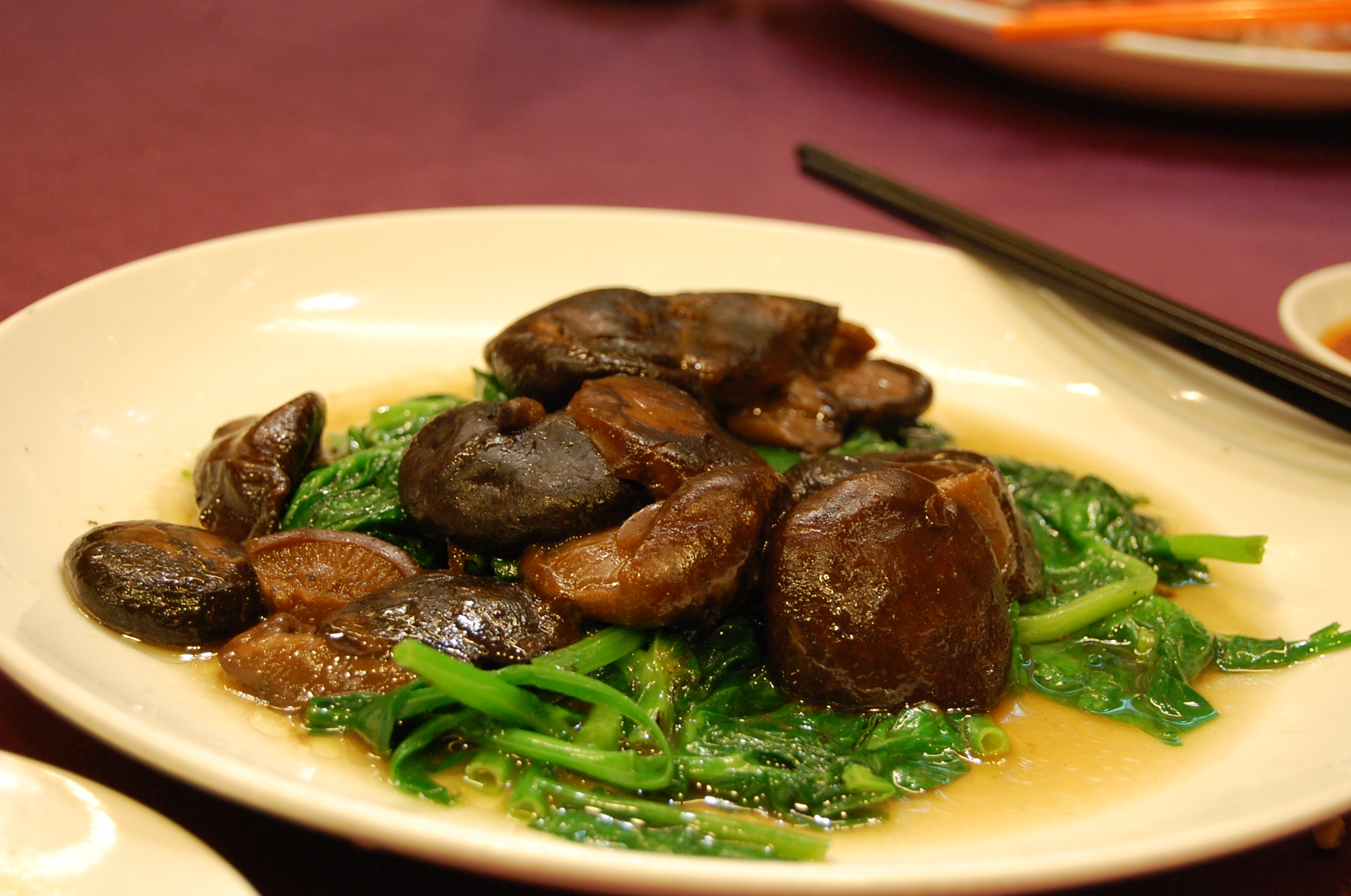 an assortment of veggies on a white plate with chopsticks