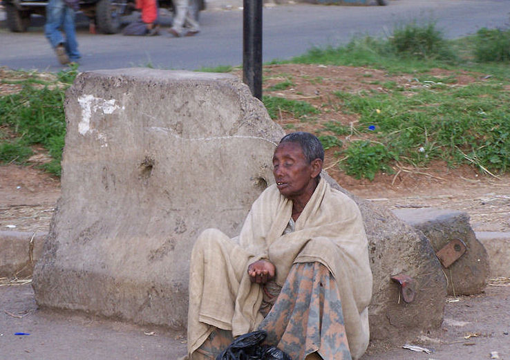 a man sitting on the sidewalk with his laundry bags