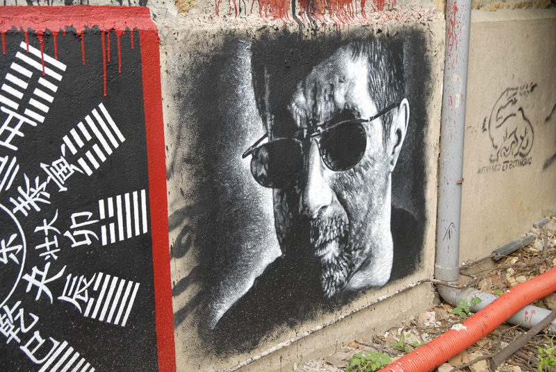 a picture of a man wearing sunglasses and sunglasses on a wall with writing