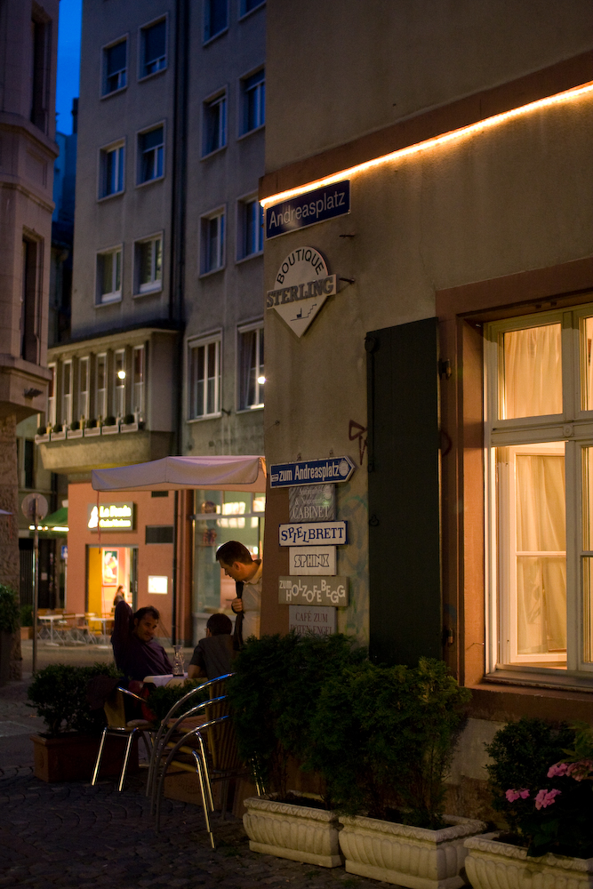 a couple of people sitting at a table in front of a building