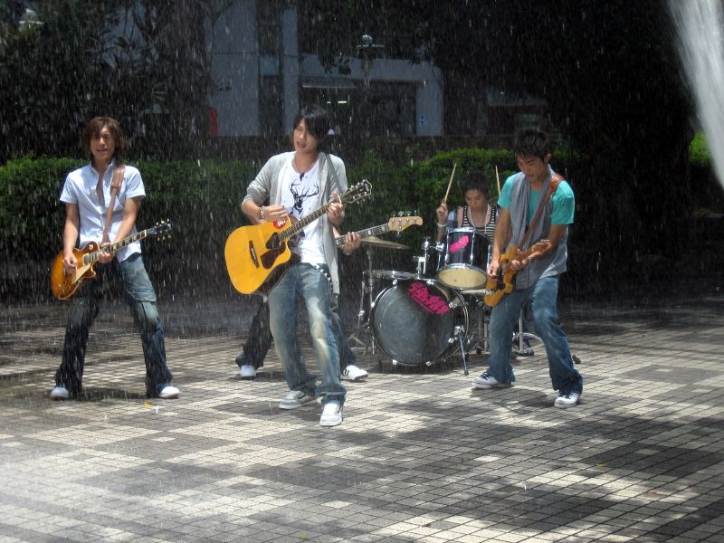 young men play music in the rain while it's raining