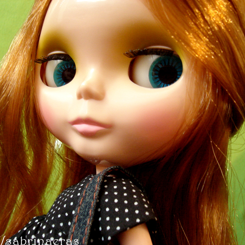 a close up of a doll face wearing glasses and polka dot dress