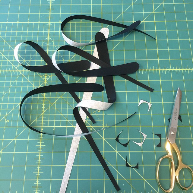 a scissors cut out of strips of paper on a  mat