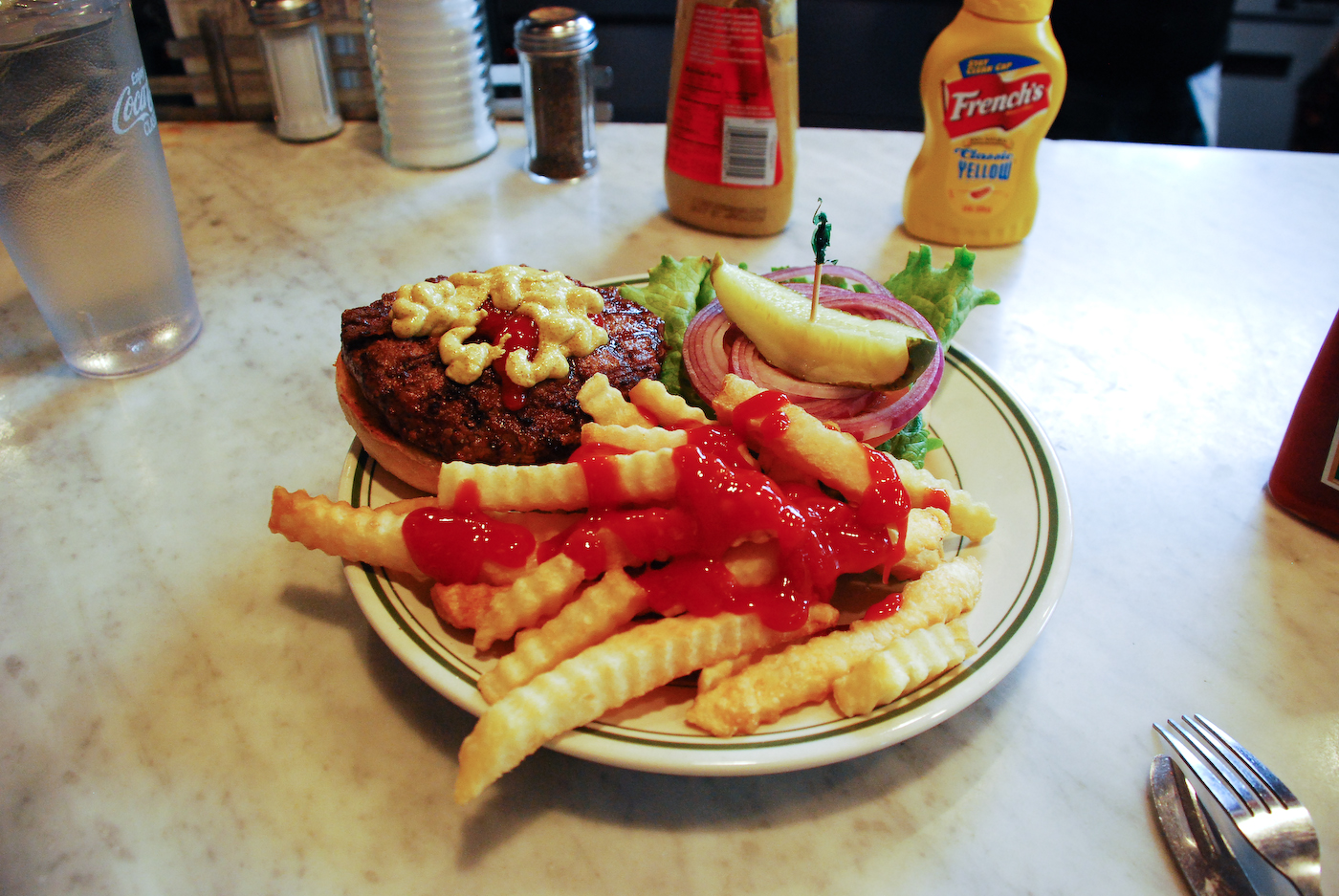 a white plate topped with french fries covered in ketchup and onions