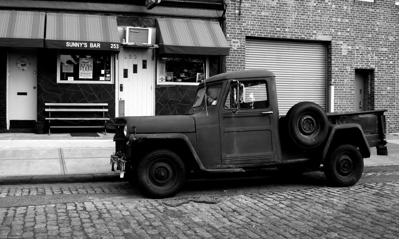 the old pick up truck is parked in front of the building