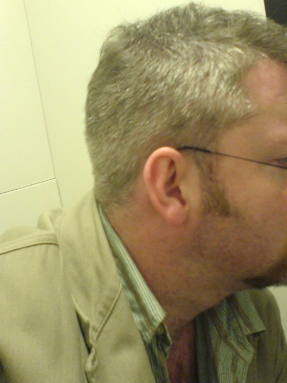 a man wearing glasses standing in front of a mirror