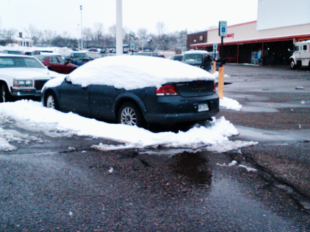 some cars are parked in the snowy parking lot