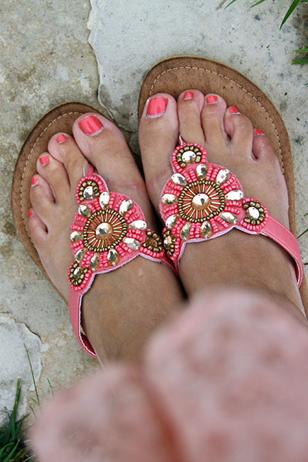 woman's legs with flowers and jewels on them next to brown sandals