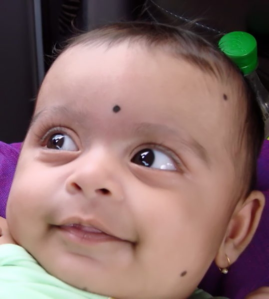 a smiling little baby wearing two green ear clips