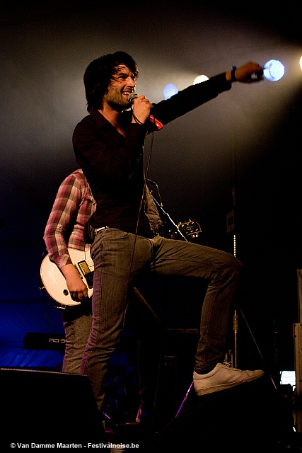 the man is holding his guitar while singing into a microphone