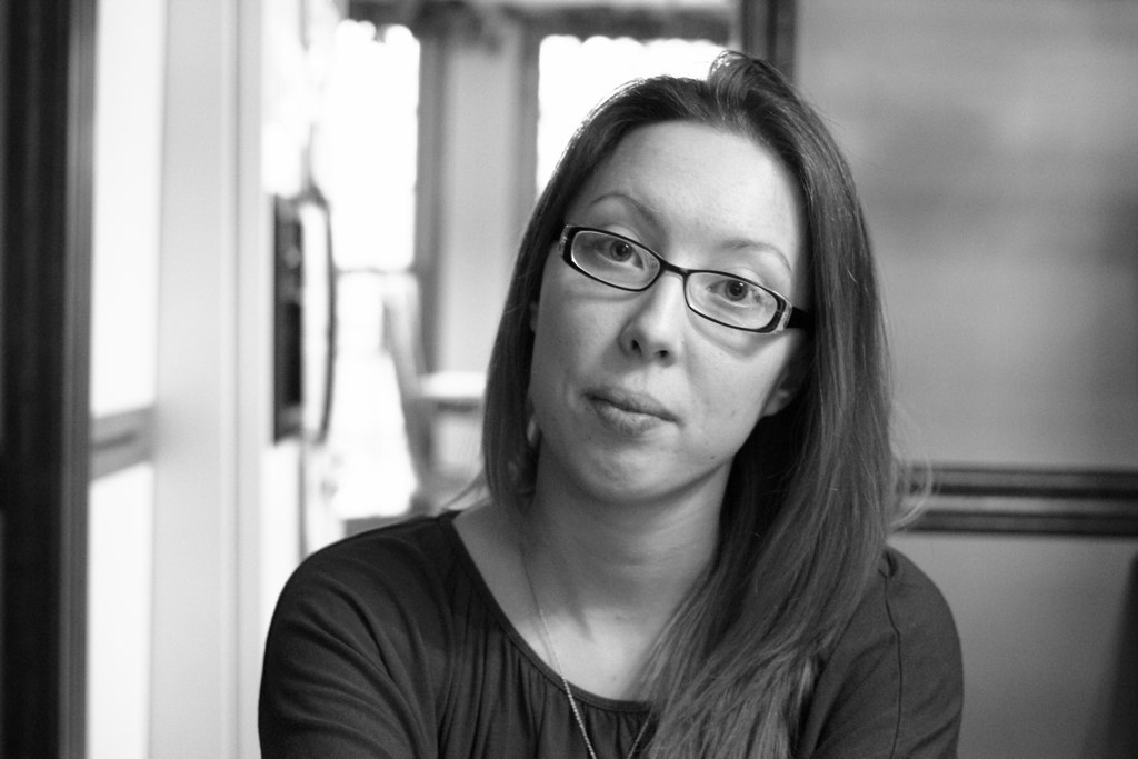 a woman wearing glasses sitting in front of a phone