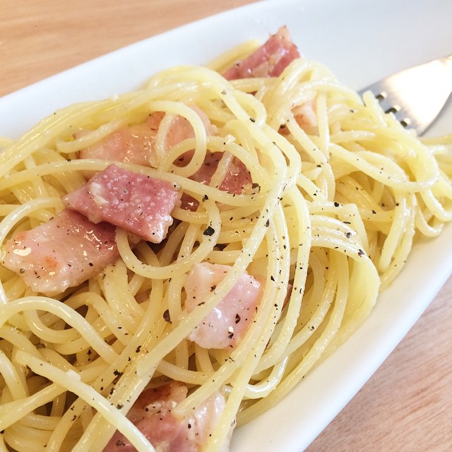 this plate is holding a dish of carbon carbone noodles with meat and parmesan cheese