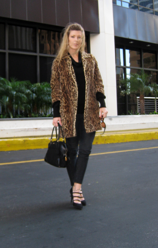 a woman wearing a leopard print coat and holding a purse