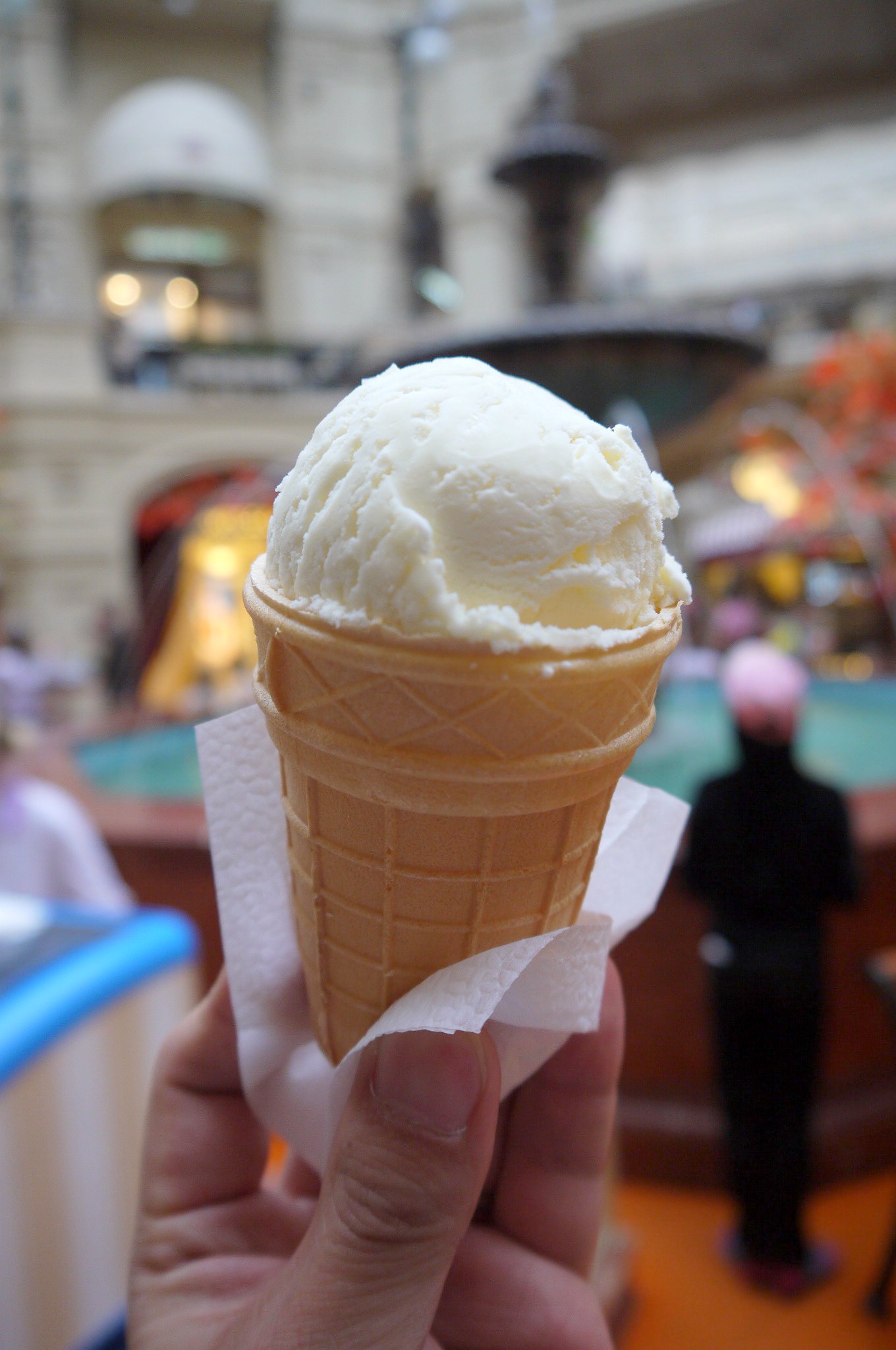 a person holds a small cone of ice cream