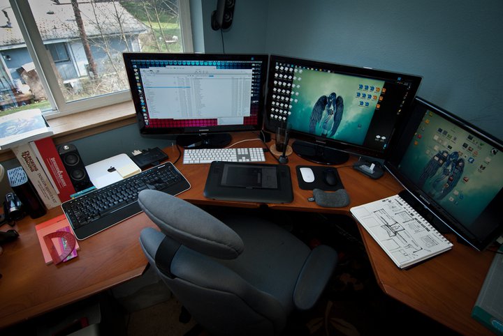 an image of a computer workstation setup with multiple monitors and keyboards