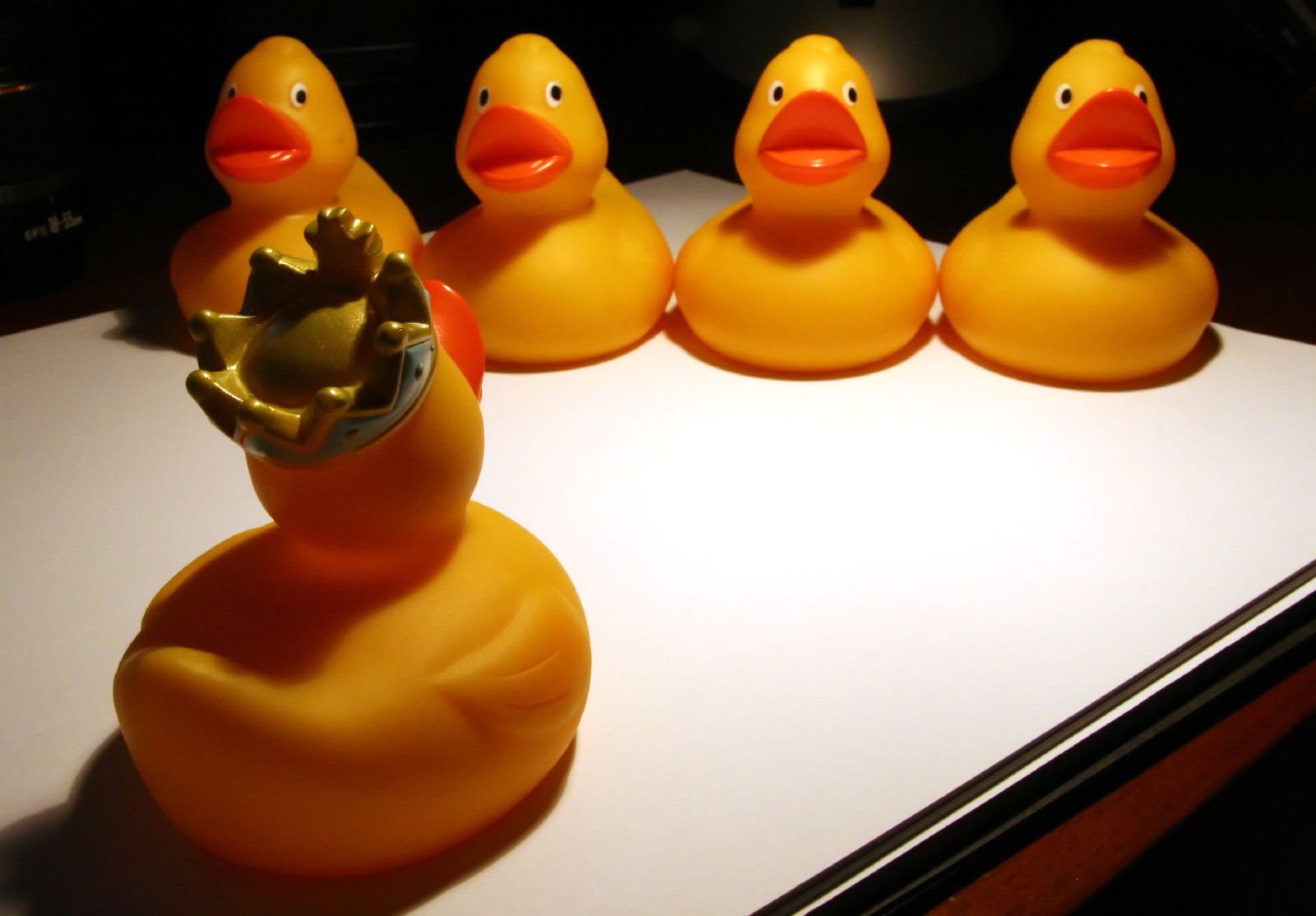 several rubber ducks on a desk with a gold crown