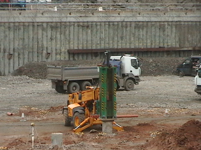 two trucks on construction site with other vehicles in background
