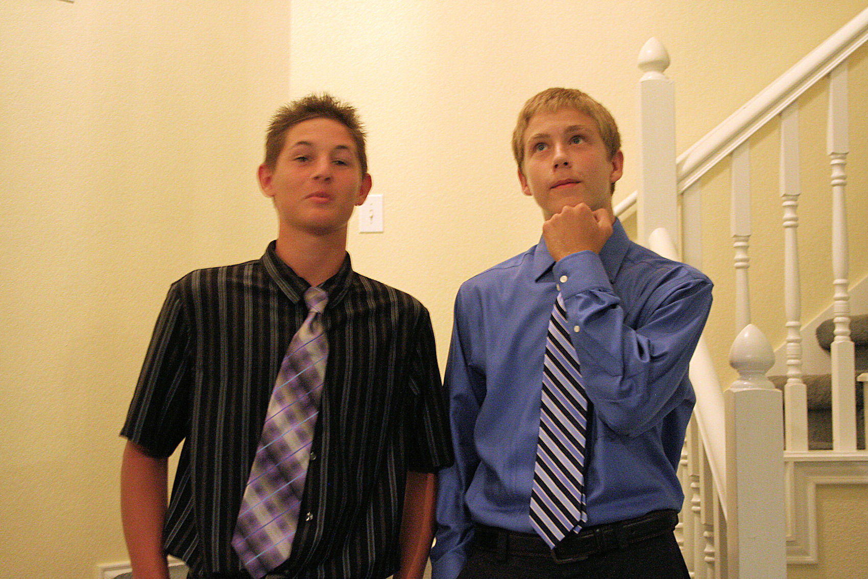 two young men pose for the camera with their neck ties on