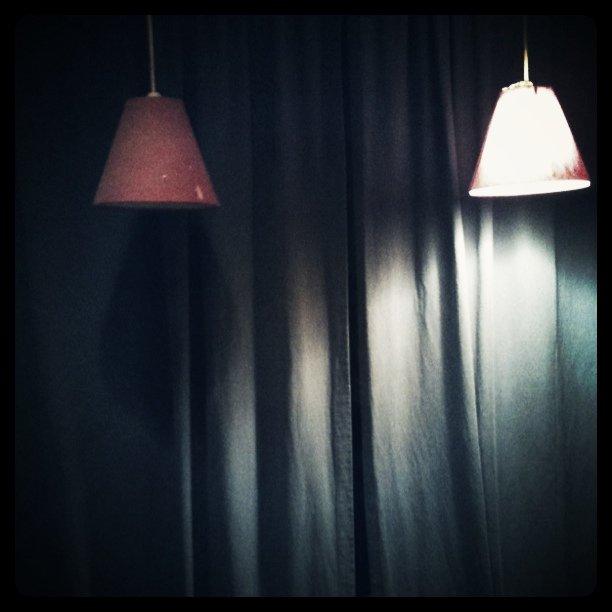 two lamps in the dark hanging on a wall