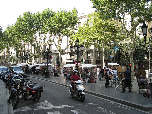 a city street lined with lots of motorcycles and pedestrians