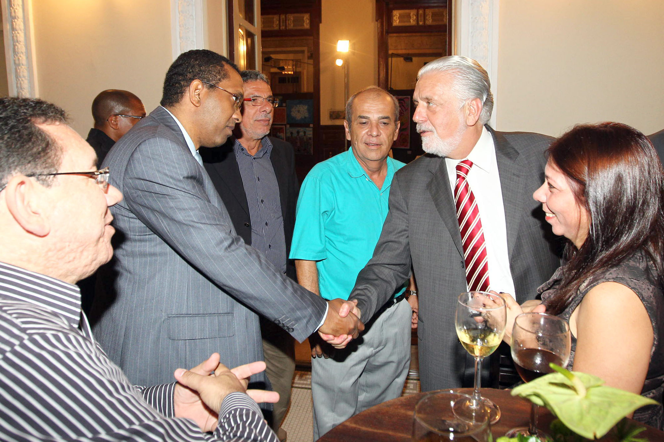 three men shaking hands in front of other people