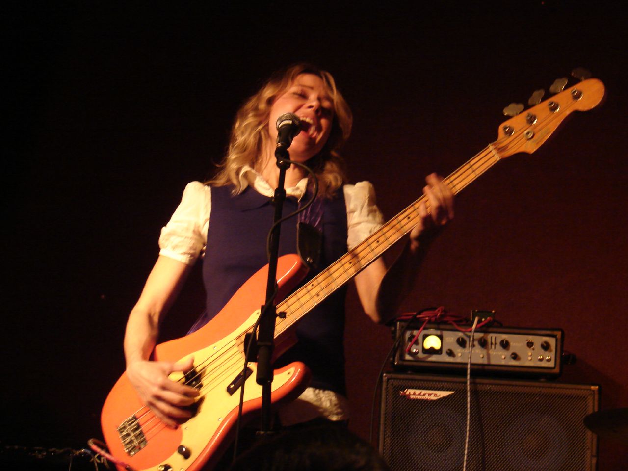 woman singing with two bass guitars in hand