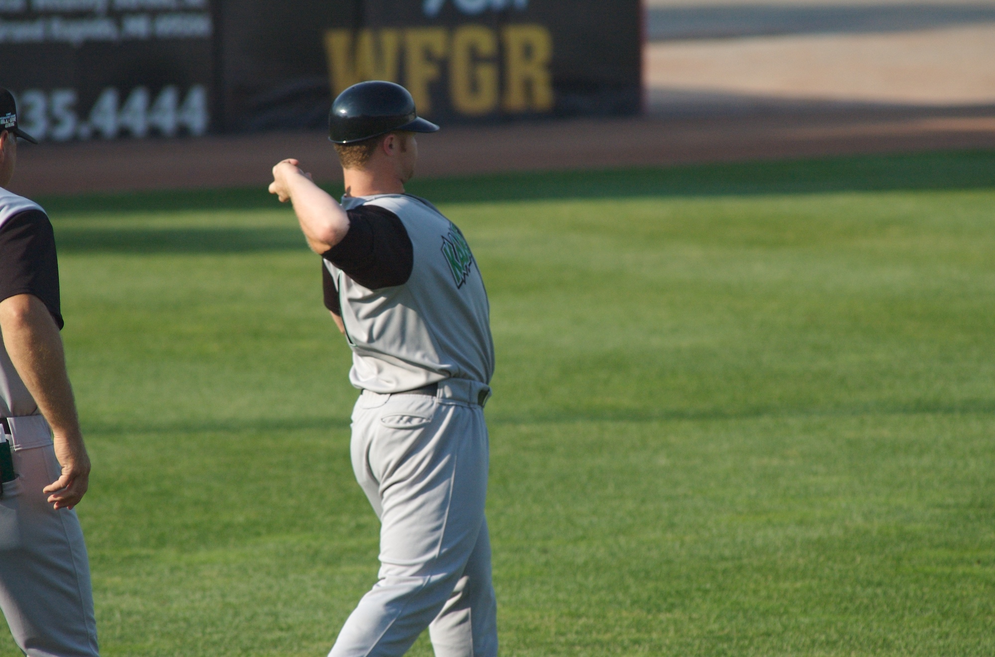 two baseball players standing on the grass looking at soing