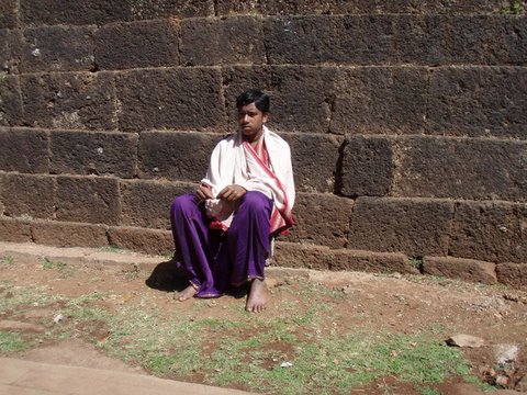 a man in an outfit sitting on the ground near brick walls
