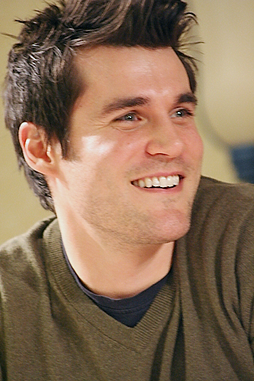 a close up of a person wearing a green shirt and a smile