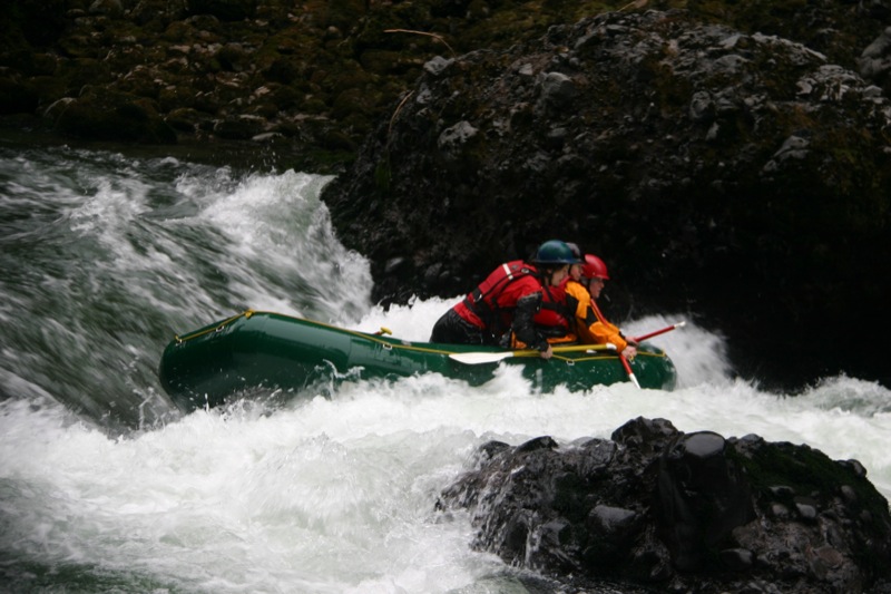 two people are paddling on a raft in rough water