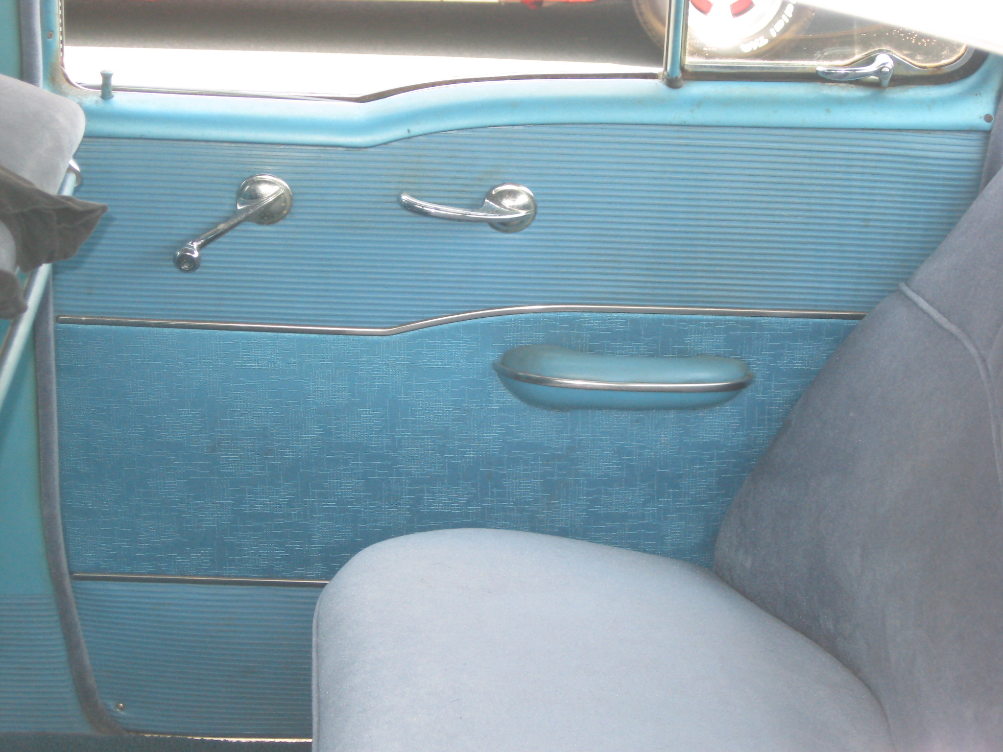 an older looking blue car interior with a handle and door s