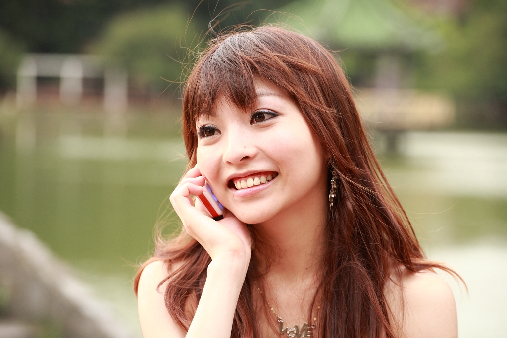 a beautiful woman sitting on a bench and talking on a cell phone