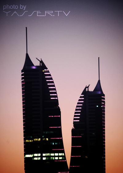 two tall buildings sit near each other at dusk