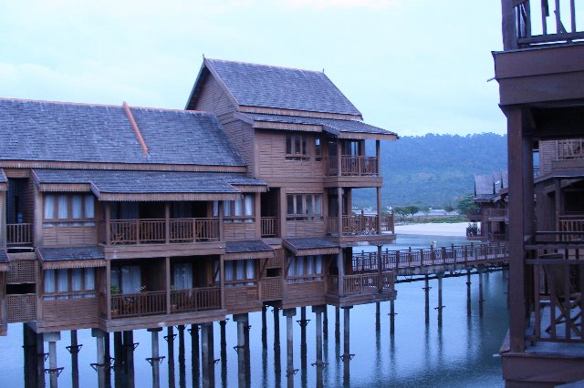 an apartment building is in the foreground as water passes by