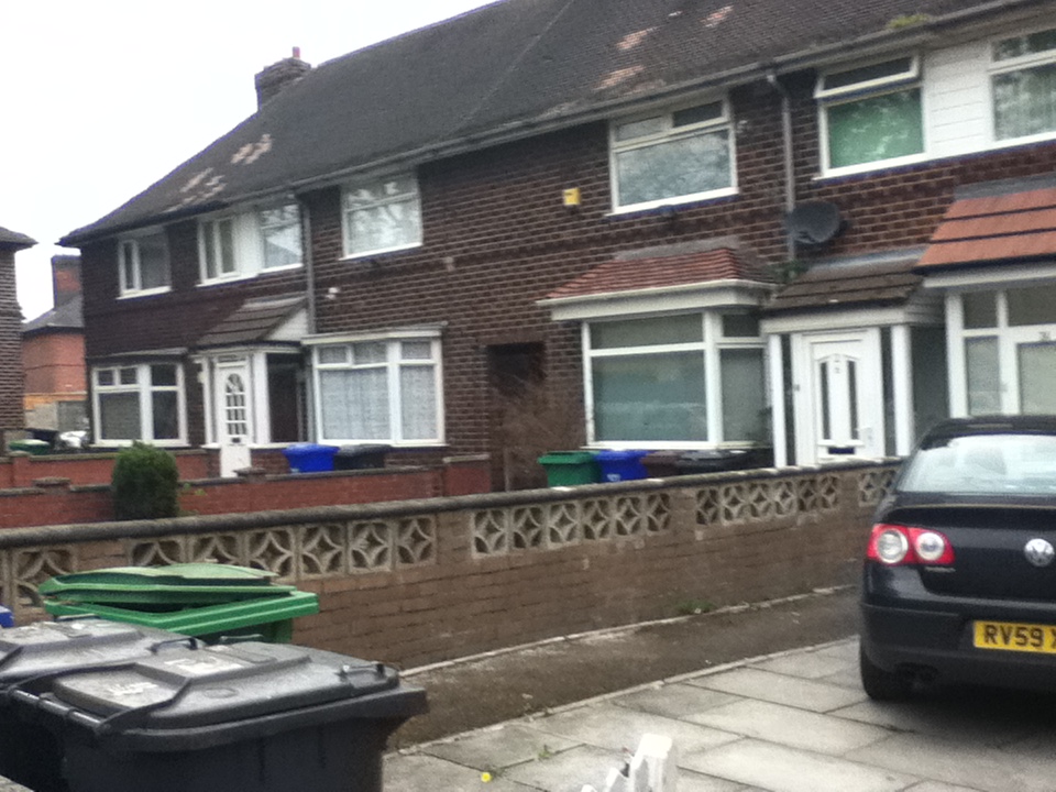 cars parked along side of a large brick house