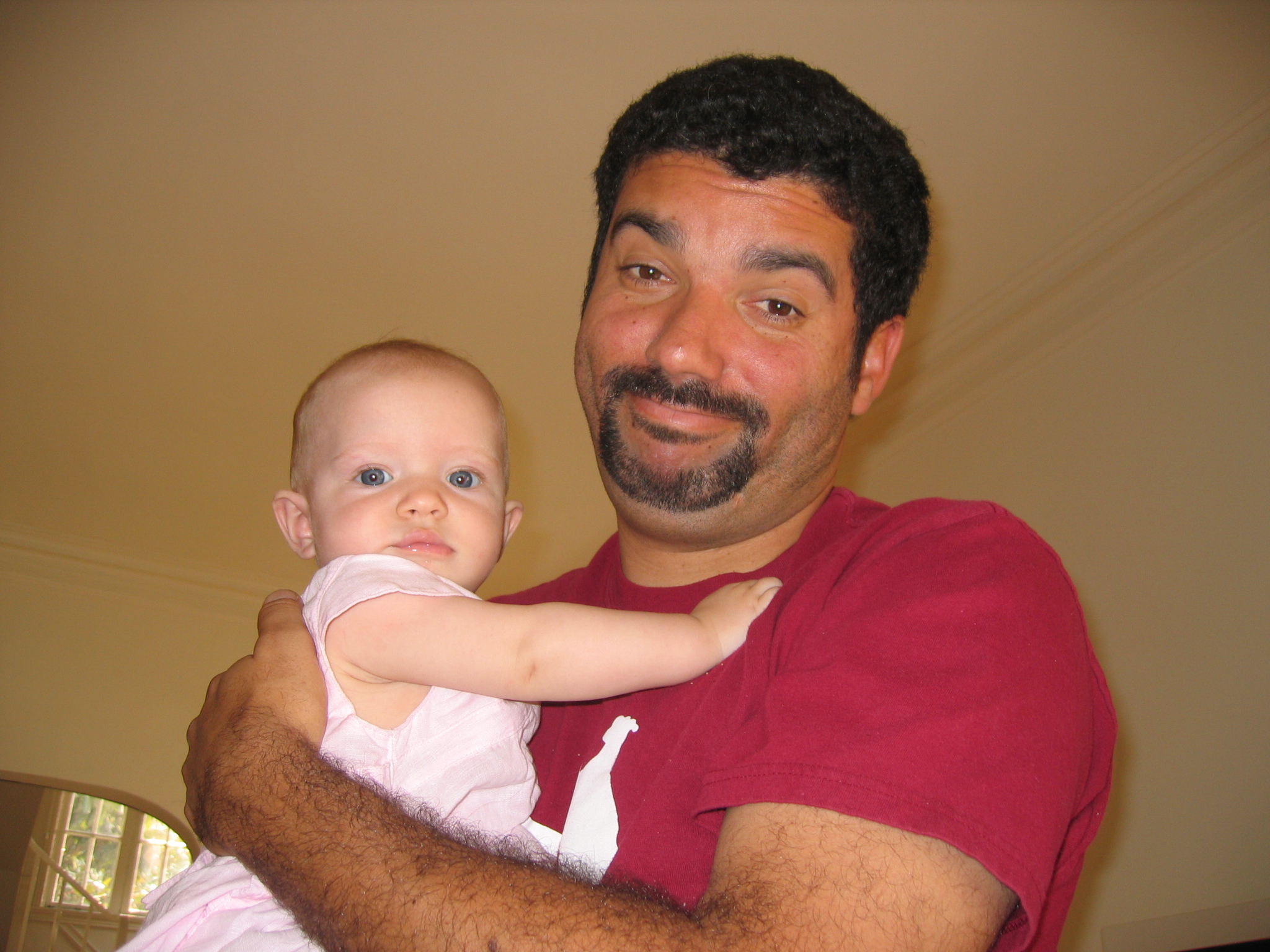 a man holding a baby and wearing a pink outfit