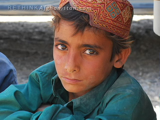 a boy with a hat and glasses, sits in front of his van