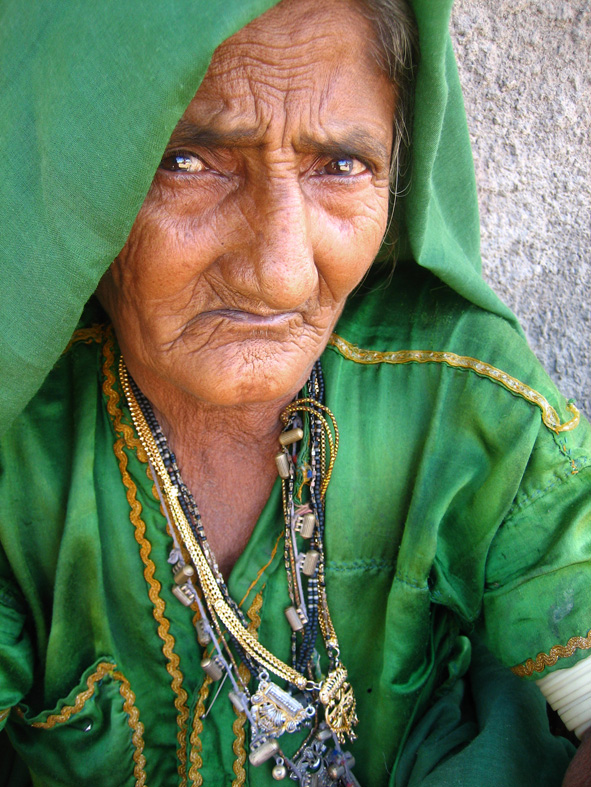 an old woman wearing jewelry and a green blanket