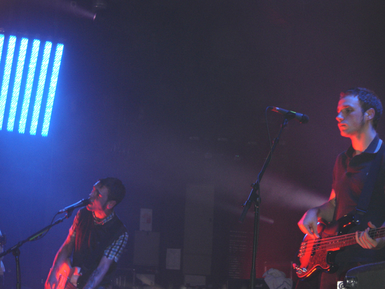 three people playing instruments on a dark stage