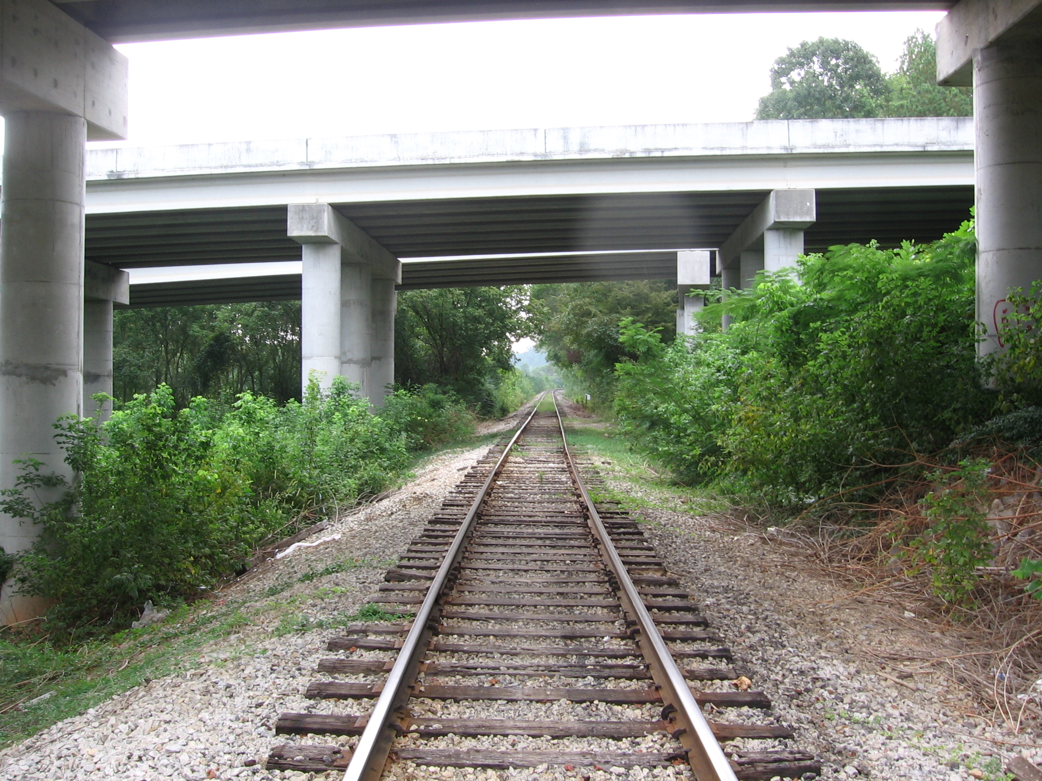 a railroad track beneath an overpass that crosses underneath an overpass