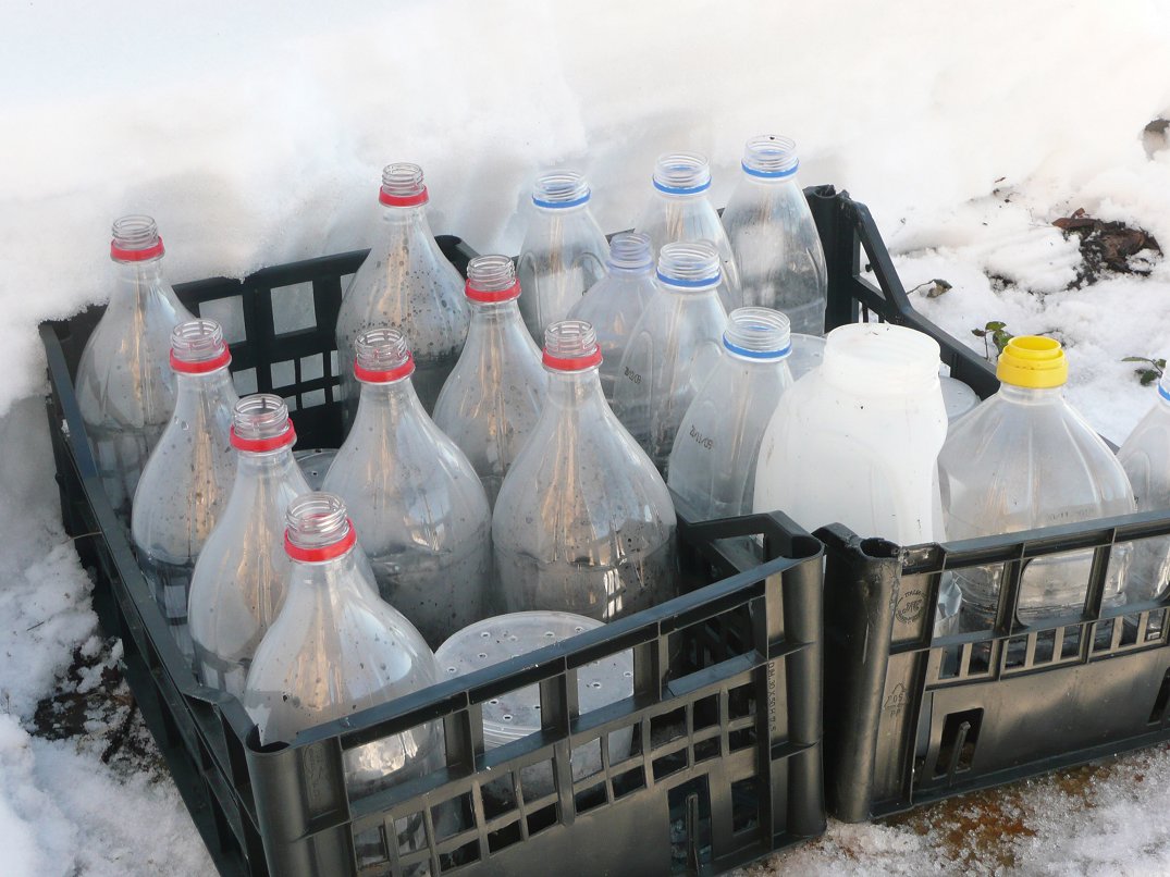 several crates and bottles filled with water in the snow