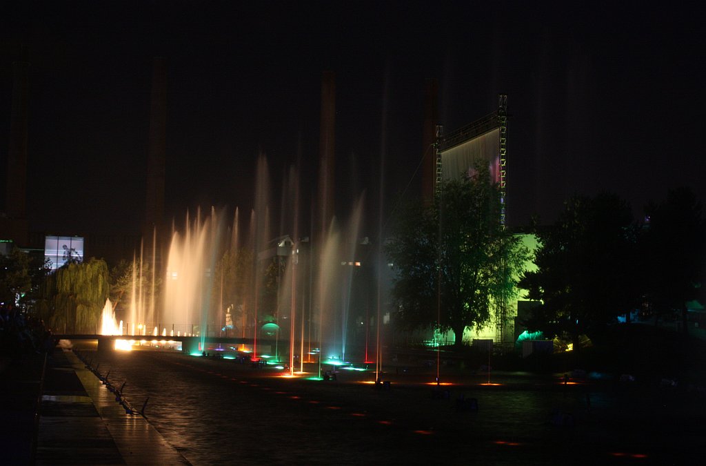 water shooting in the night sky over a park and trees