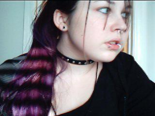 the young woman with her long purple hair looks at soing in her mouth