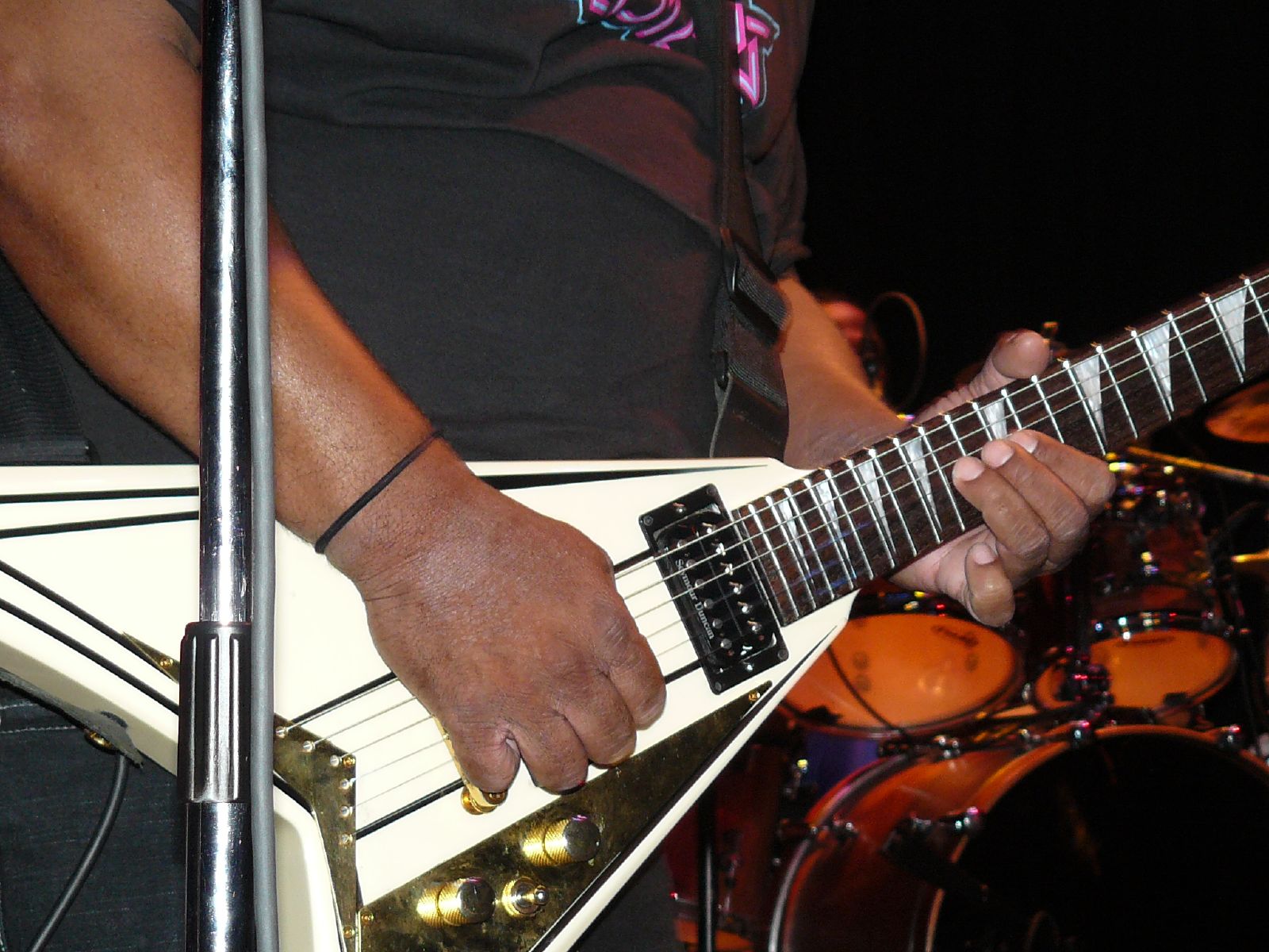 man playing a guitar with a set of drums behind him