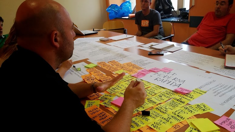 people at a conference sitting around a table filled with post - it notes