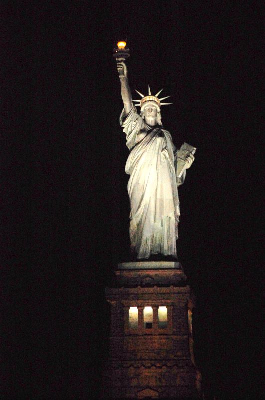the statue of liberty lit up at night in new york city