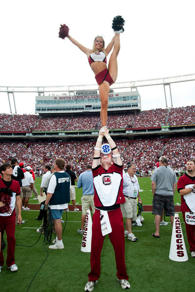 two cheerleaders performing tricks at a game
